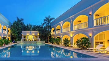 Un complejo turístico con piscina central, varios balcones y un área exterior bien iluminada.