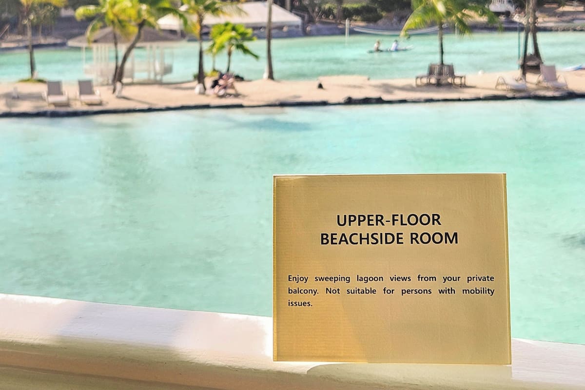 Schild für ein Strandzimmer im Obergeschoss mit Blick auf eine Lagune und Palmen.