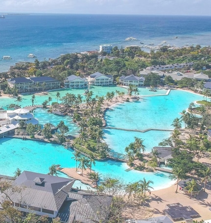 A resort with multiple swimming pools, beachfront villas, and a view of the ocean.. Plantation Bay a Real Resort with a Real Spa