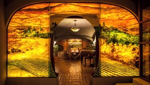An arched doorway with a view of a dining area and a piano.
