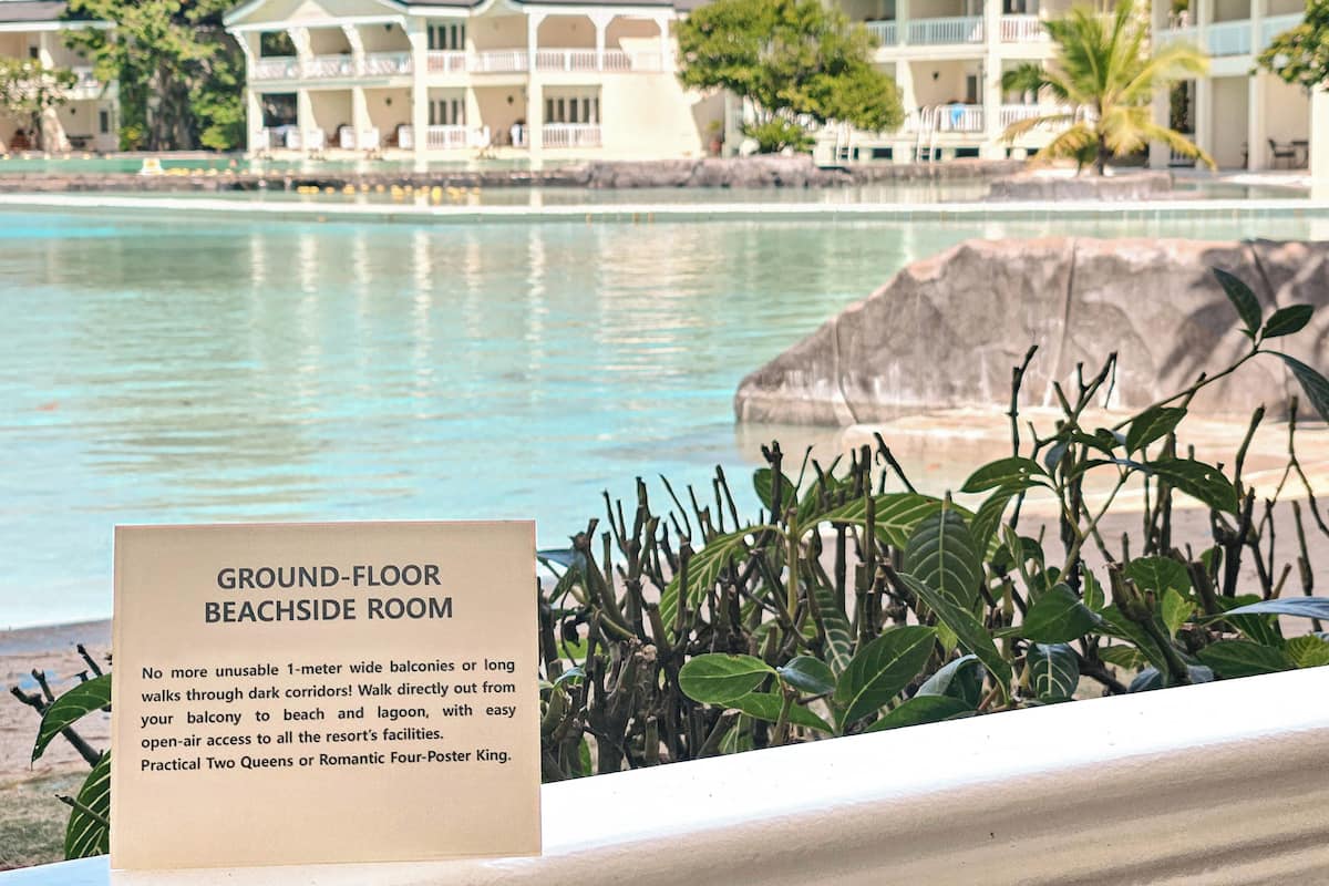 Schild für ein Zimmer im Erdgeschoss mit direktem Strandzugang und Blick auf Pool und Hotelgebäude.