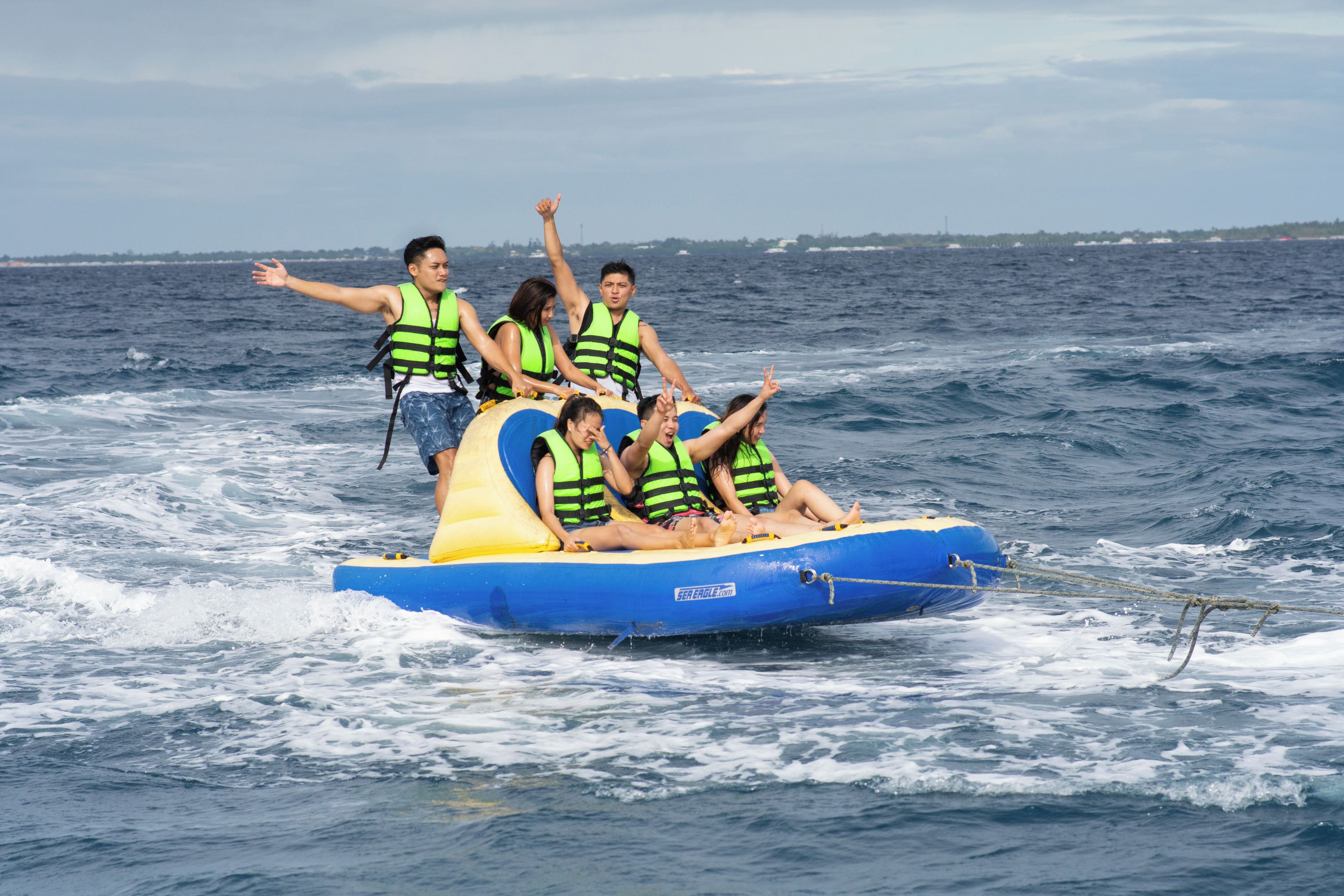 Un grupo de personas en una balsa inflable azul y amarilla con chalecos salvavidas, flotando en el agua.