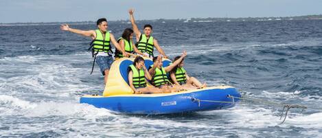 Un grupo de personas en una balsa inflable azul y amarilla con chalecos salvavidas, flotando en el agua.