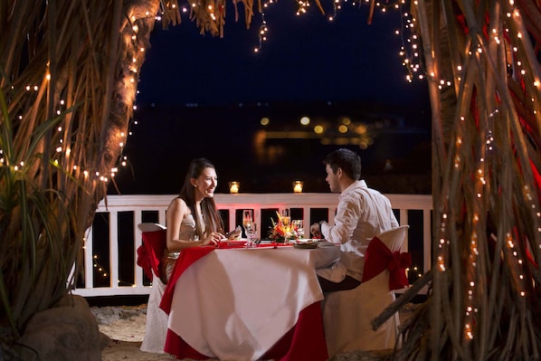 An outdoor dining setup with a table and chairs, surrounded by string lights and palm fronds. -  Plantation Bay a Real Resort with a Real Spa (Lapu-Lapu)