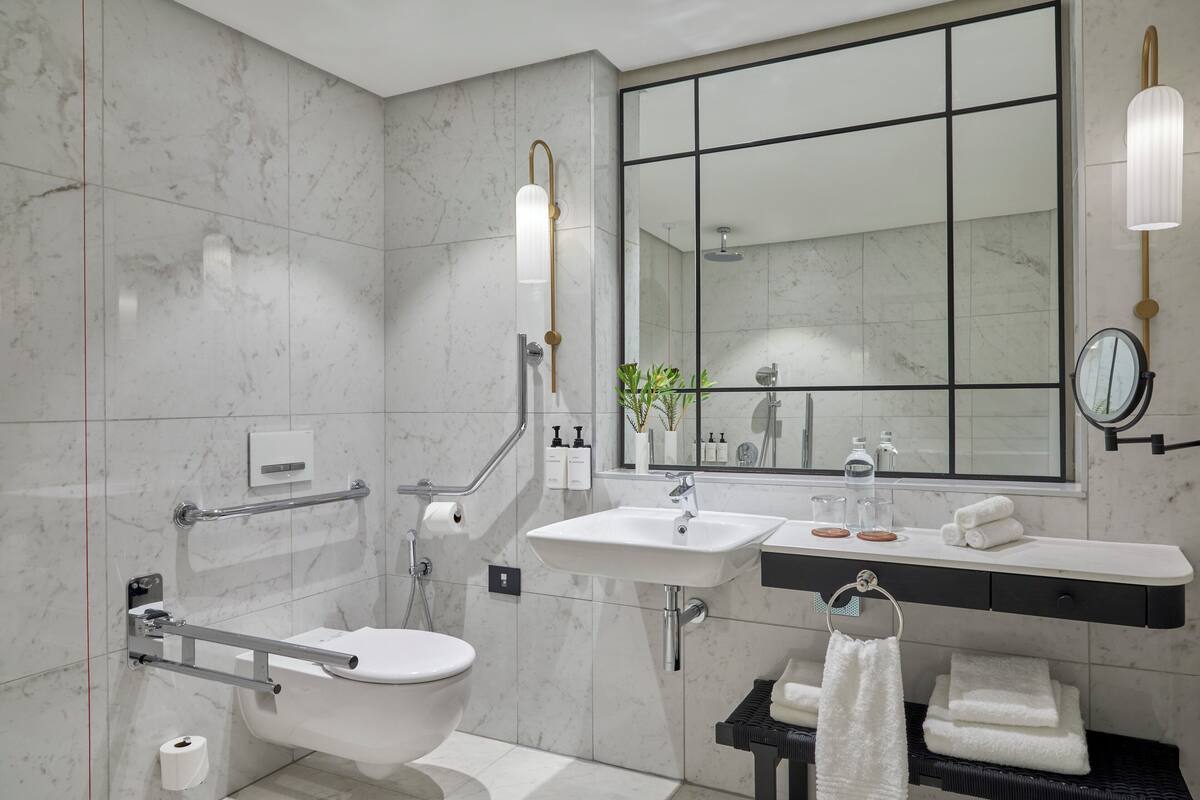A modern bathroom with a toilet, bidet, sink, and mirror.