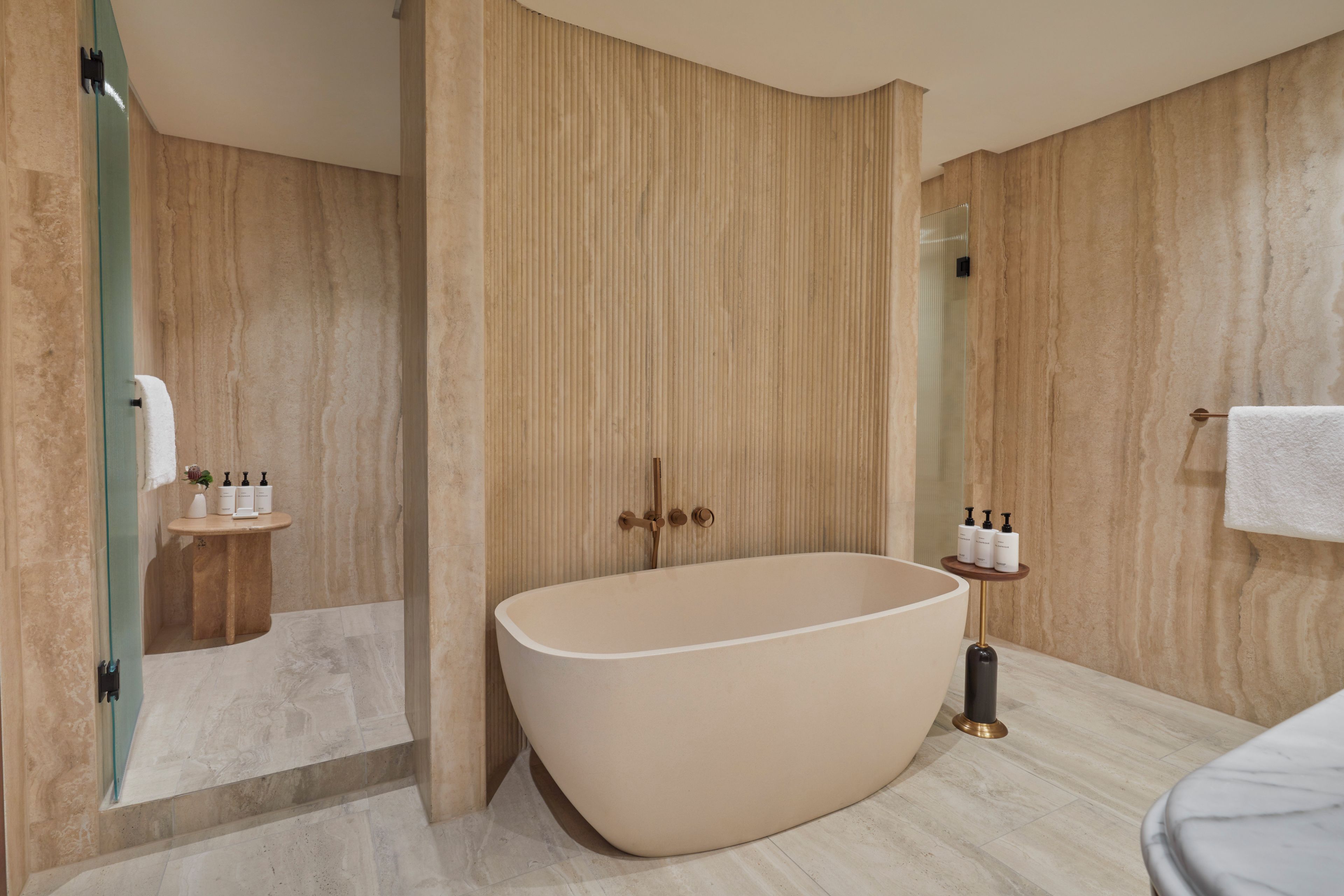 Une salle de bain moderne avec une baignoire sur pieds, une douche à parois de verre et un meuble-lavabo avec des articles de toilette.
