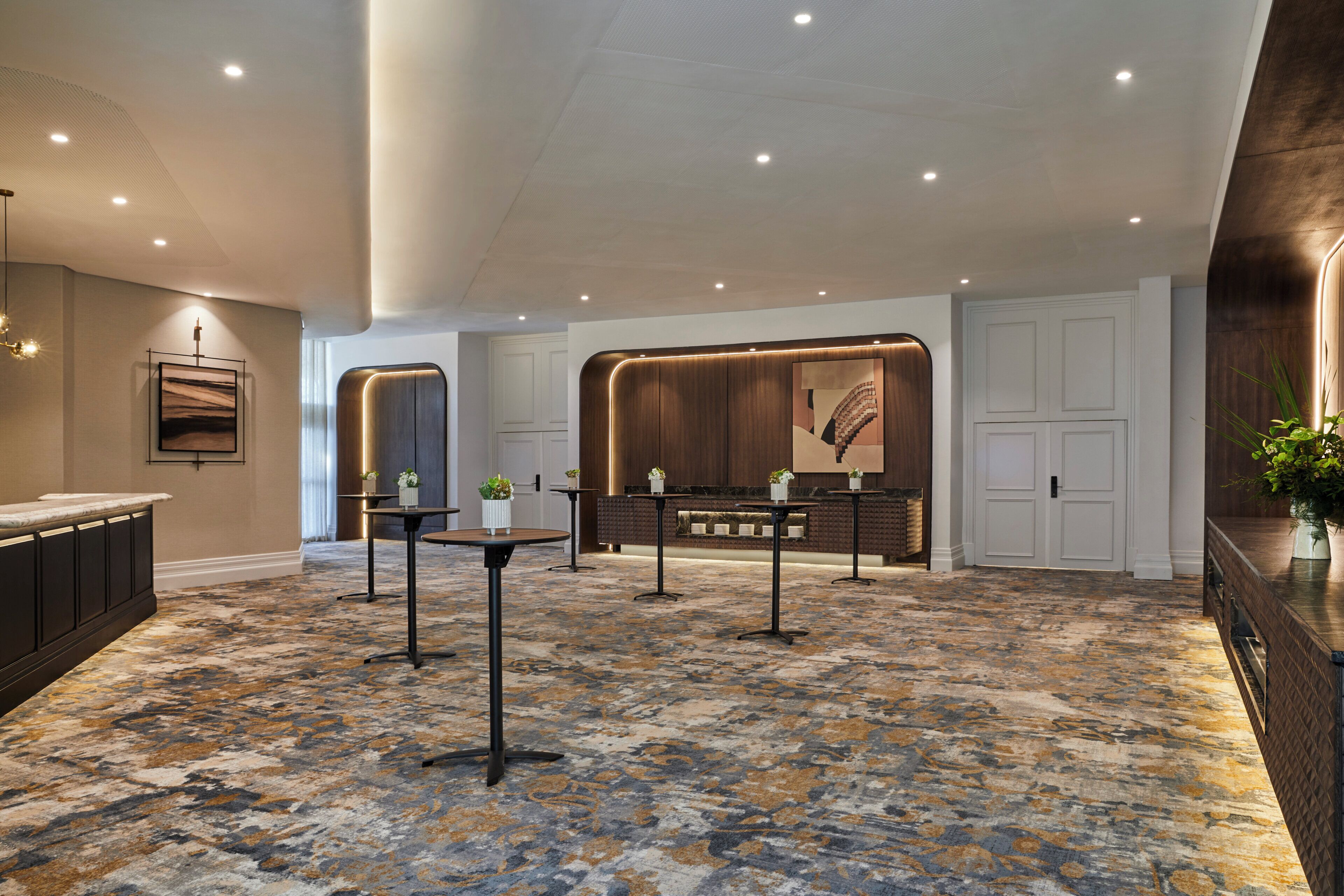A hotel lobby with a marble floor, a reception desk, and a large wall art piece.