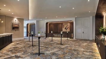 A hotel lobby with a marble floor, a reception desk, and a large wall art piece.