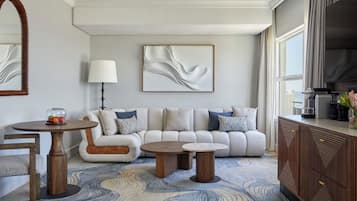 A modern living room with a sofa, two round tables, a coffee machine, and a large window.