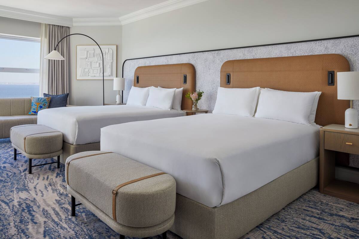 A hotel room with two beds, a sofa, a small table, and a lamp.