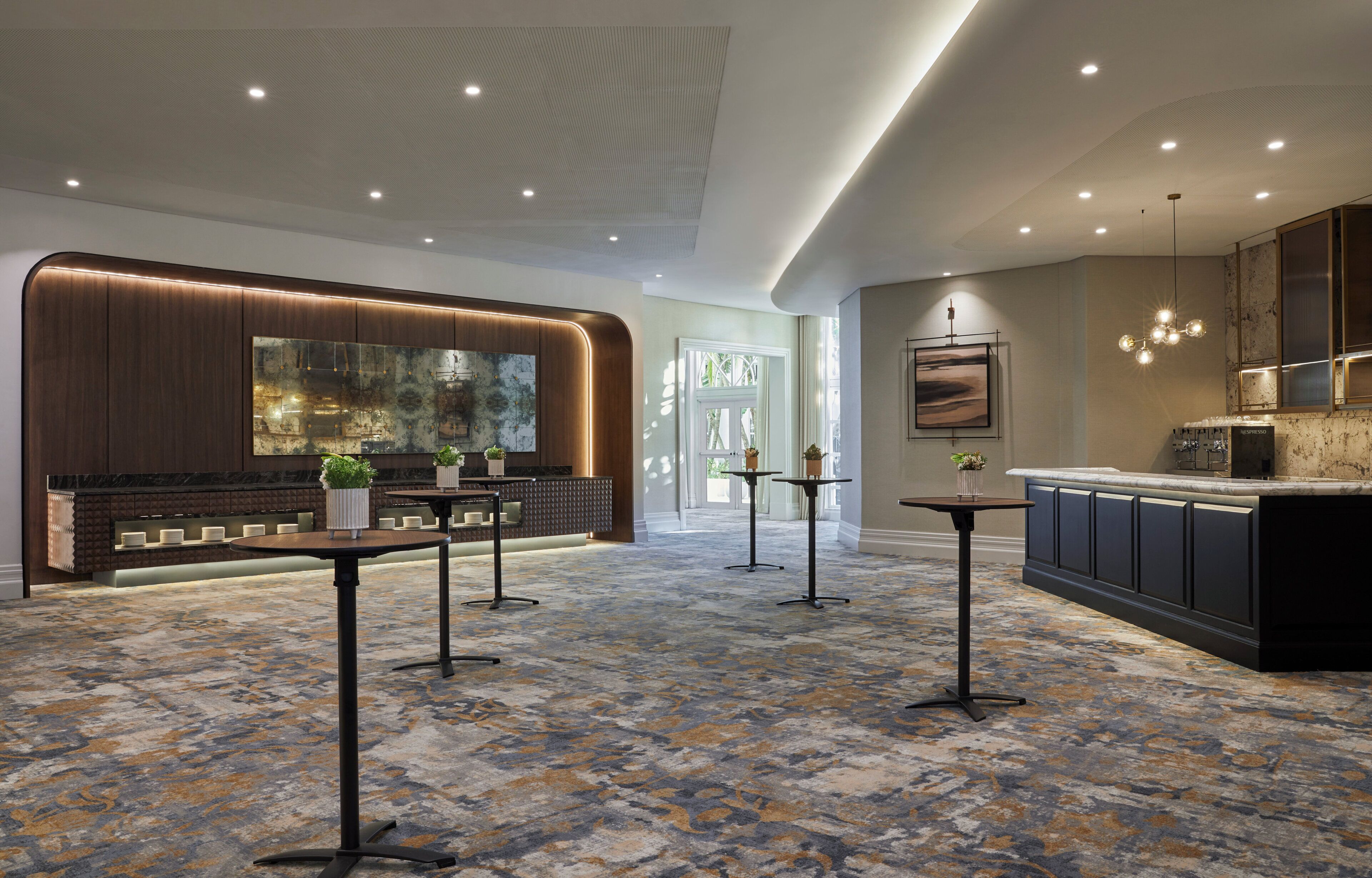 A modern hotel lobby with a reception desk, seating area, and a kitchen area.