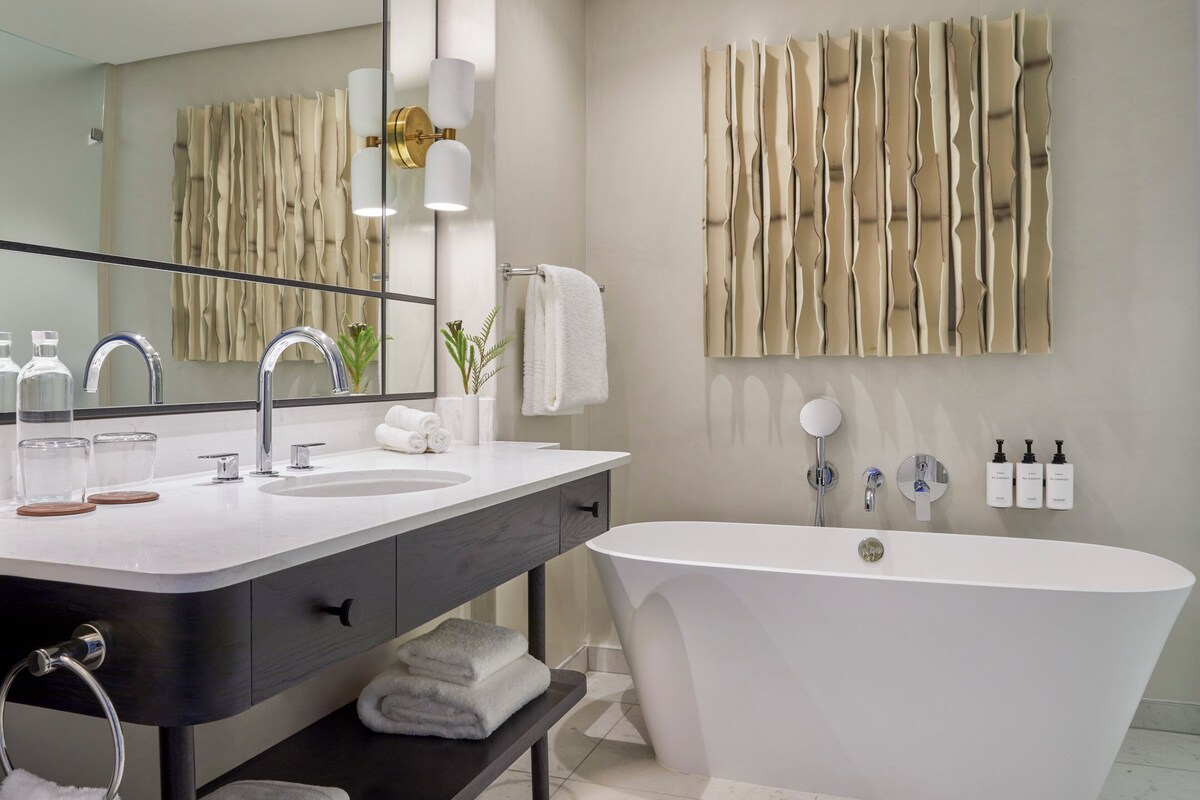 A modern bathroom with a freestanding bathtub, a double sink vanity, and a large mirror.
