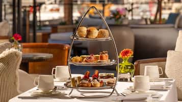 A tiered dessert stand with pastries and a vase of flowers on a table.
