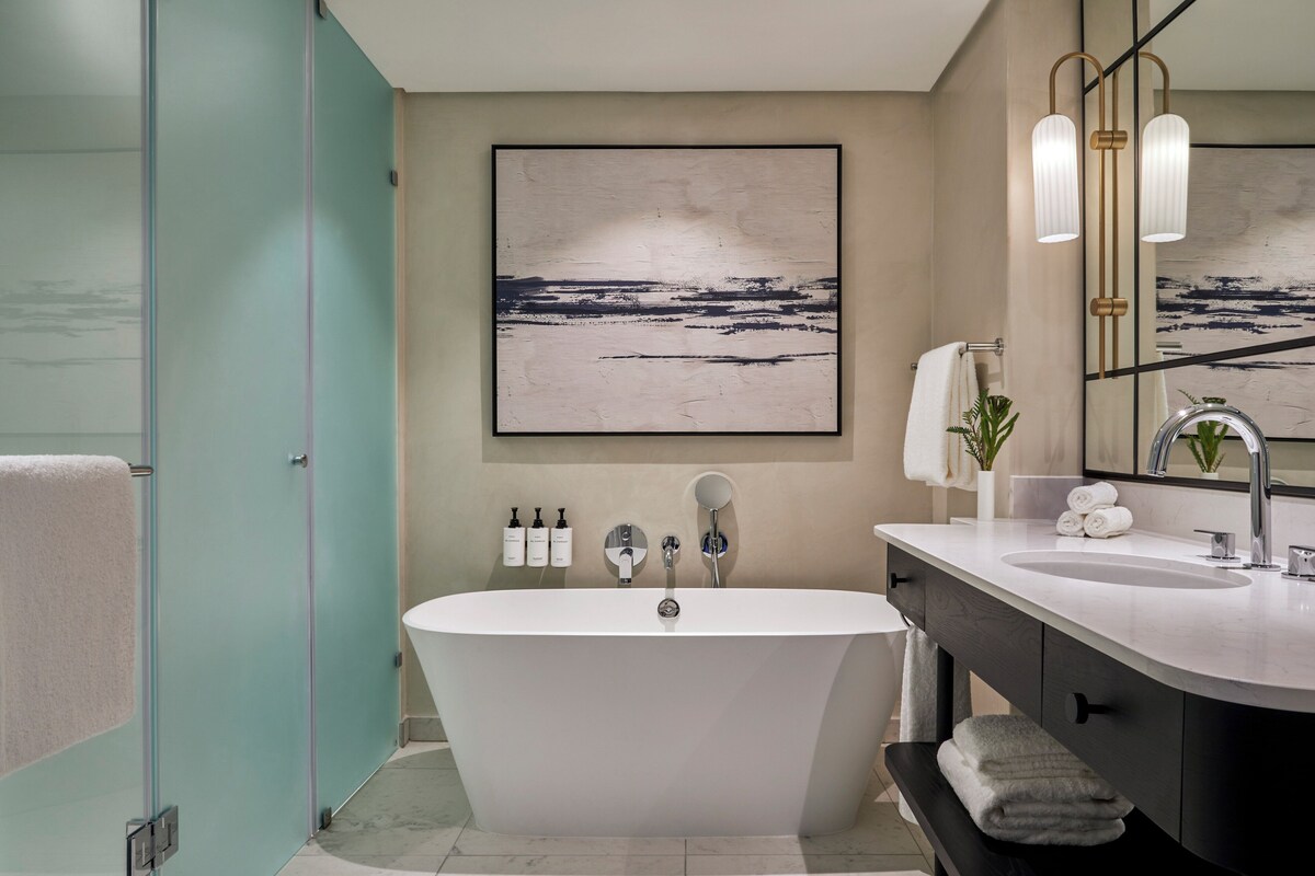 A modern bathroom with a freestanding bathtub, a vanity with a sink, and a large mirror.