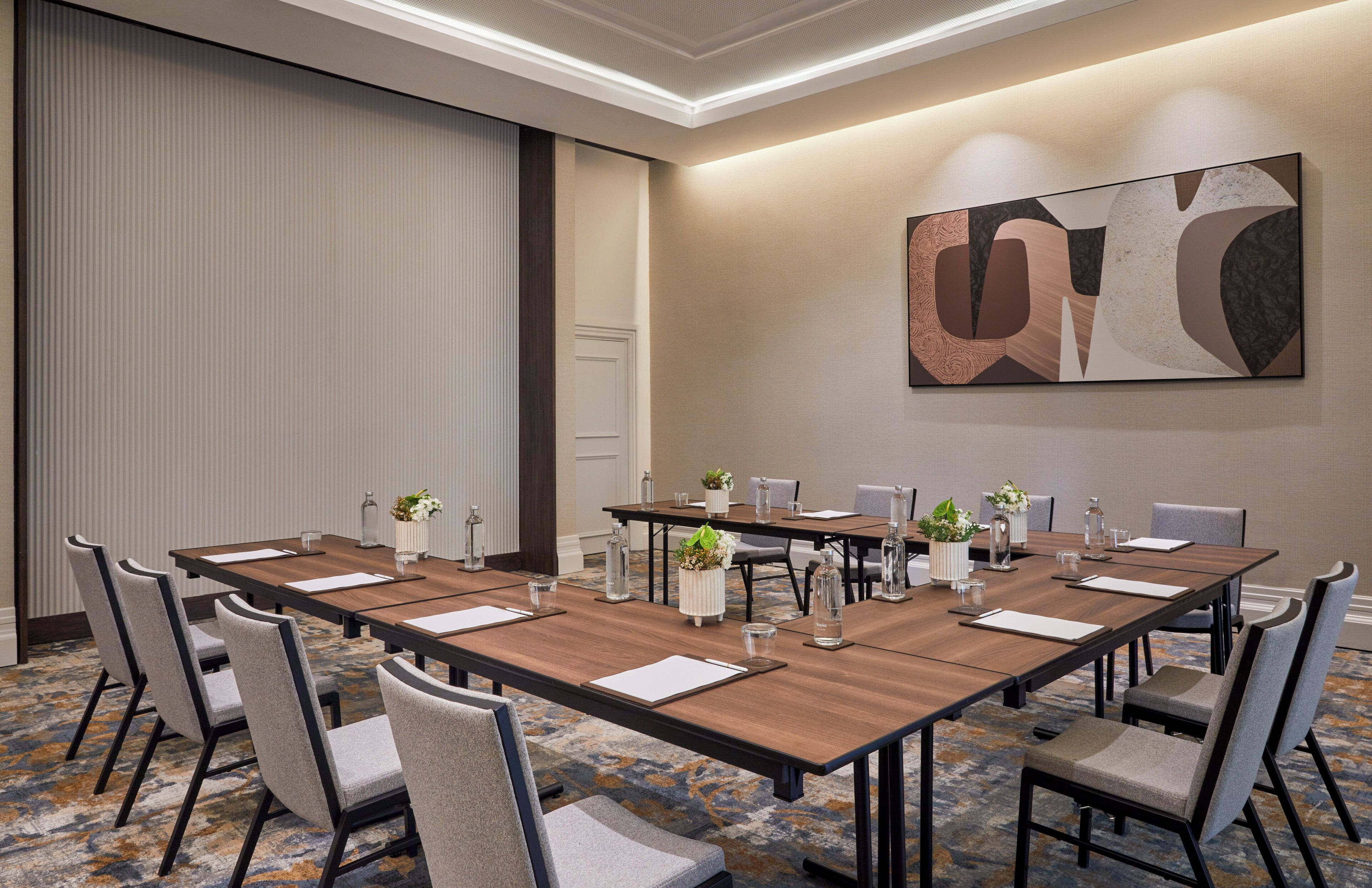 A conference room with a long table, chairs, and decorative vases.