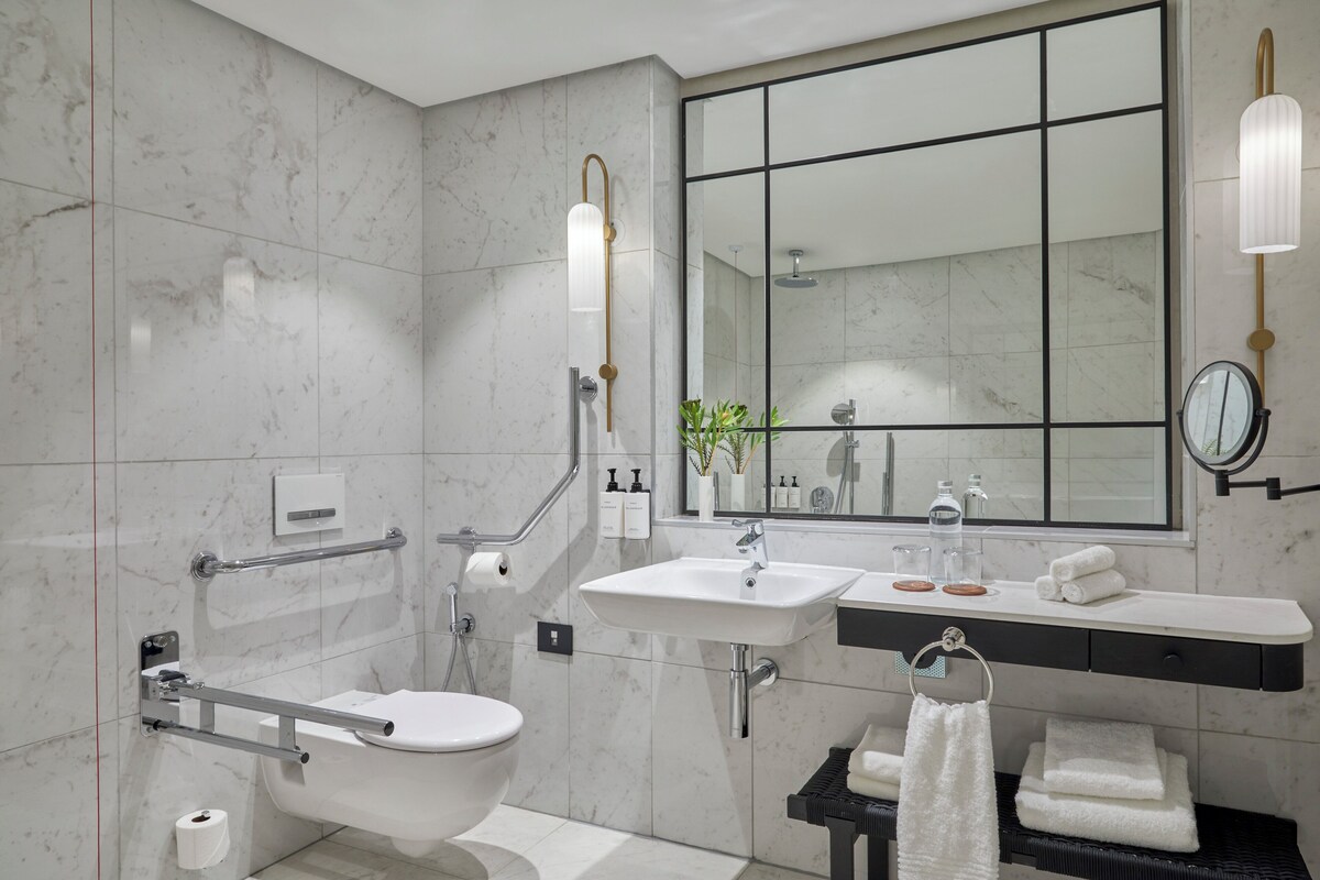 A modern bathroom with a toilet, bidet, sink, and mirror.