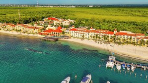 An aerial view of a coastal resort with multiple buildings, a beach, and a marina with boats. - All Ritmo Cancun Resort & Water Park - All Inclusive (Cancun)