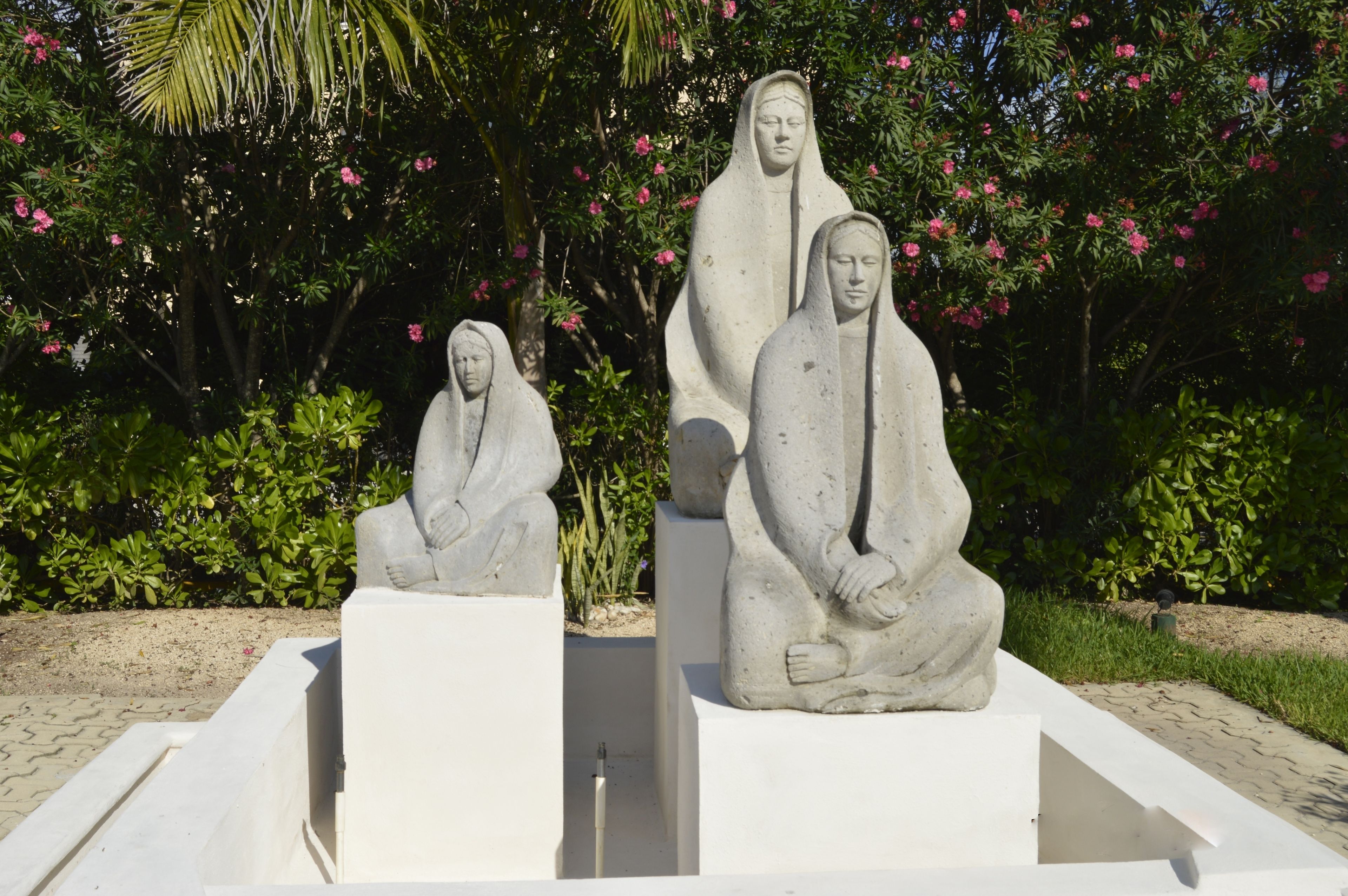 A garden with three stone statues of seated figures.