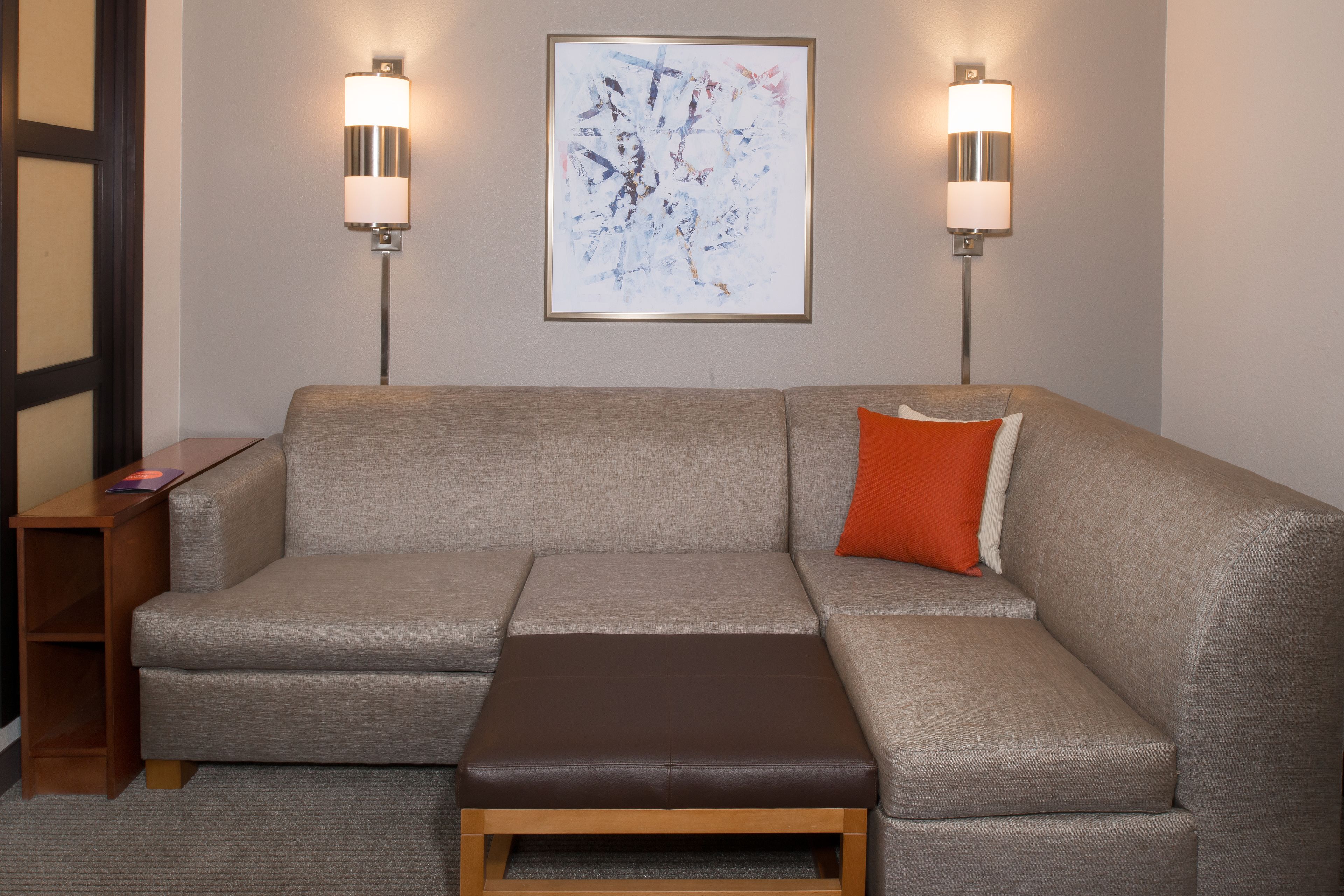 Ein modernes Wohnzimmer mit einem grauen Sofa, einem Holztisch und zwei Wandleuchten.