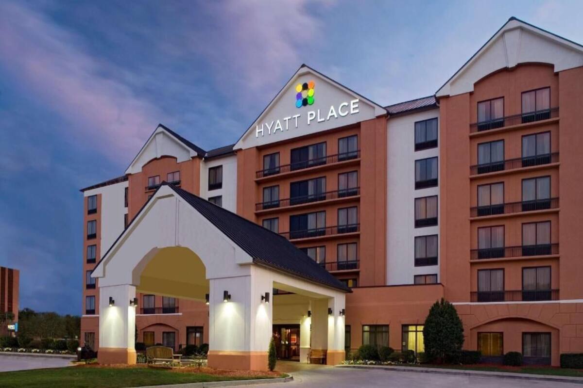 Un hôtel à plusieurs étages, reconnaissable à son grand panneau « Hyatt Place », doté d’une entrée abritée et d’un parking.