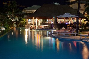 A pool area with lounge chairs and umbrellas, a bar, and a building with a thatched roof. - Blu-Zea Resort by Double-Six (Seminyak)