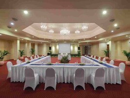 A conference room with a long table, white chairs, and chandeliers.