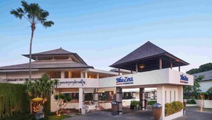 A resort with a covered entrance, palm trees, and a sign reading "Bhu-Zea Resort by Unibisak". - Blu-Zea Resort by Double-Six (Seminyak)