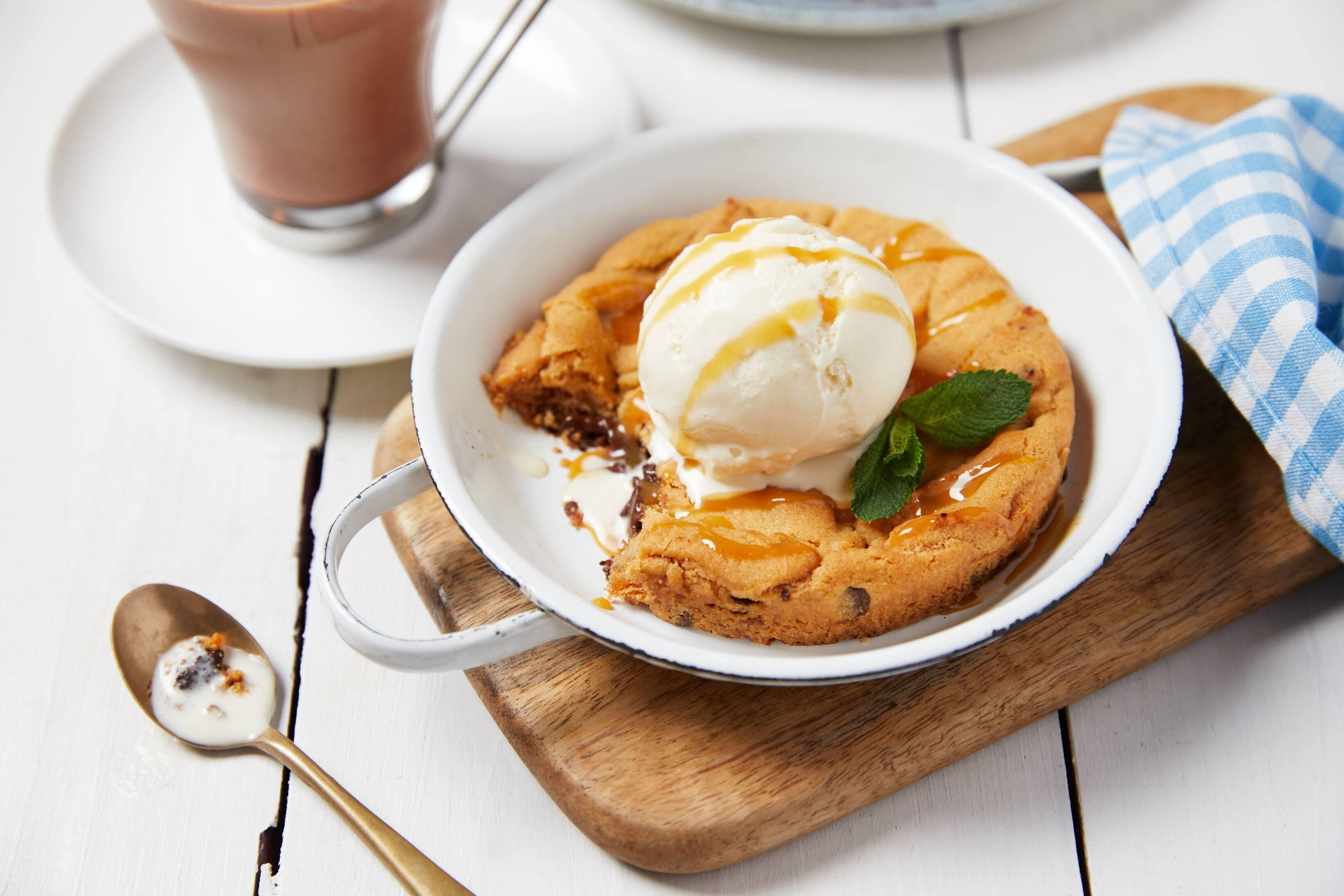 A dessert with a scoop of ice cream on top, served in a white bowl on a wooden board.