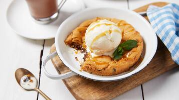 A dessert with a scoop of ice cream on top, served in a white bowl on a wooden board.