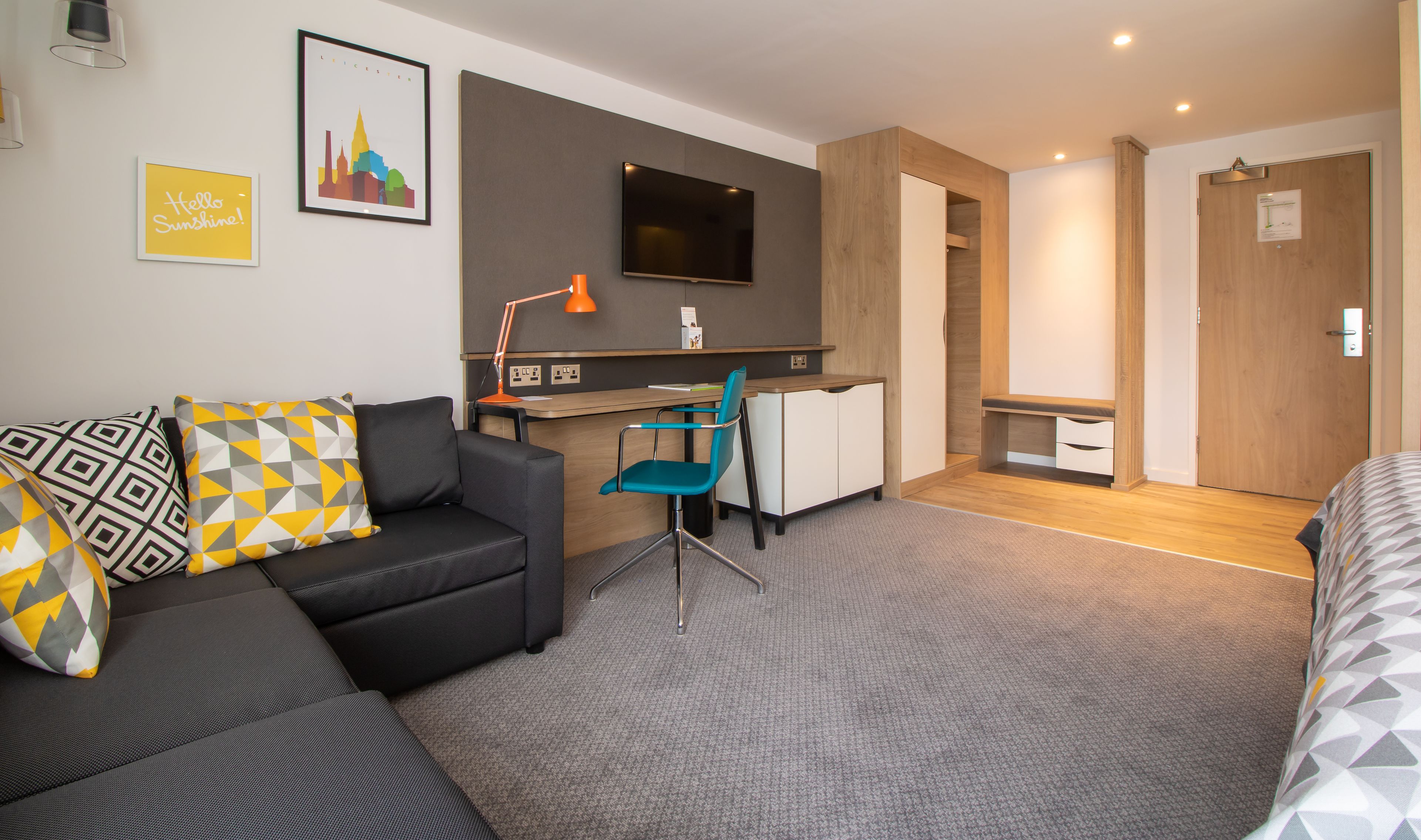 Ett modernt hotellrum med en soffa, ett skrivbord, en stol och en säng.