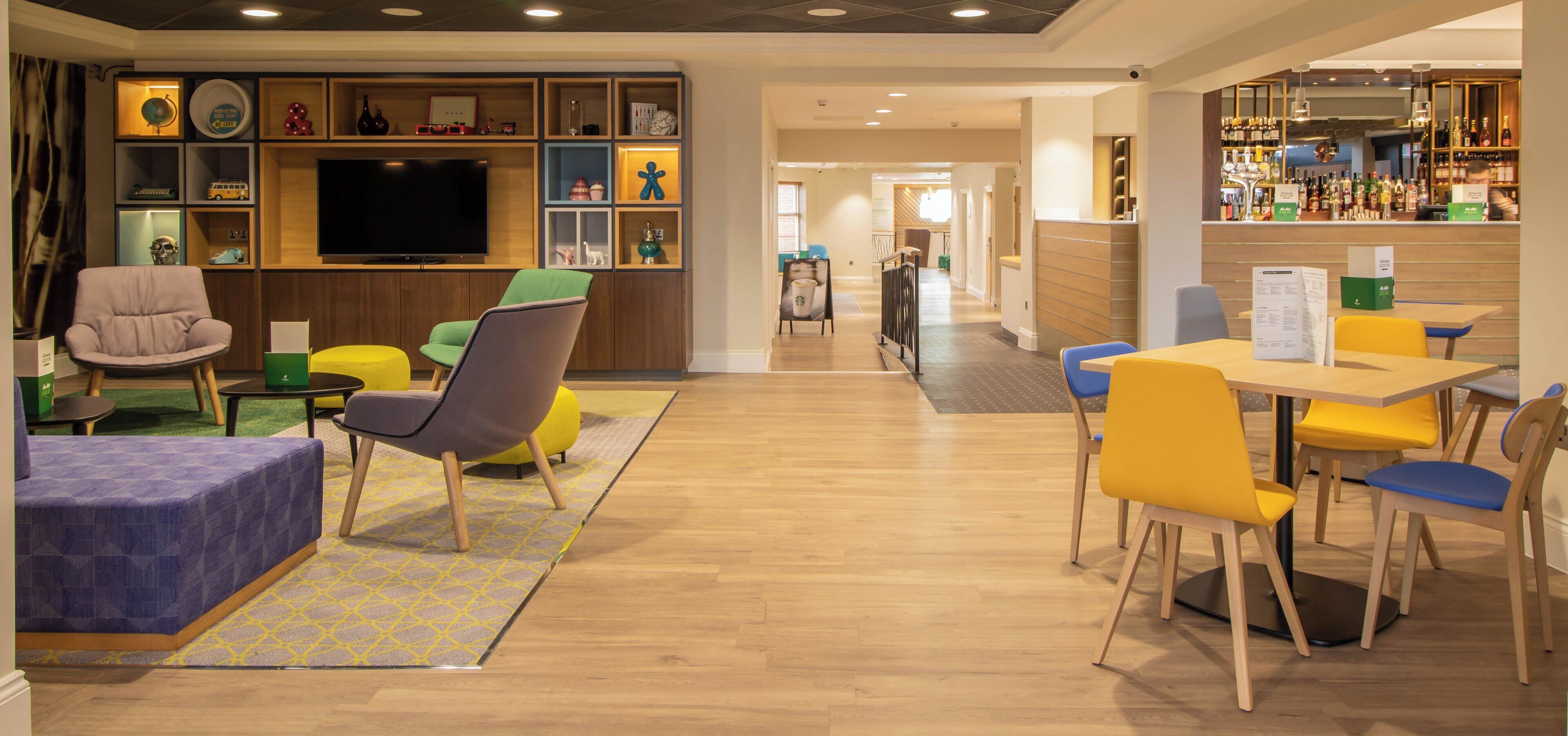 A hotel lobby with a bar area, seating arrangements, and a television.