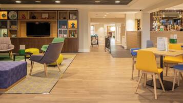 A hotel lobby with a bar area, seating arrangements, and a television.