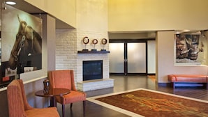 A lobby with a stone fireplace, a large horse portrait, and a bench. - Hampton Inn & Suites N. Ft. Worth-Alliance Airport (Fort Worth)