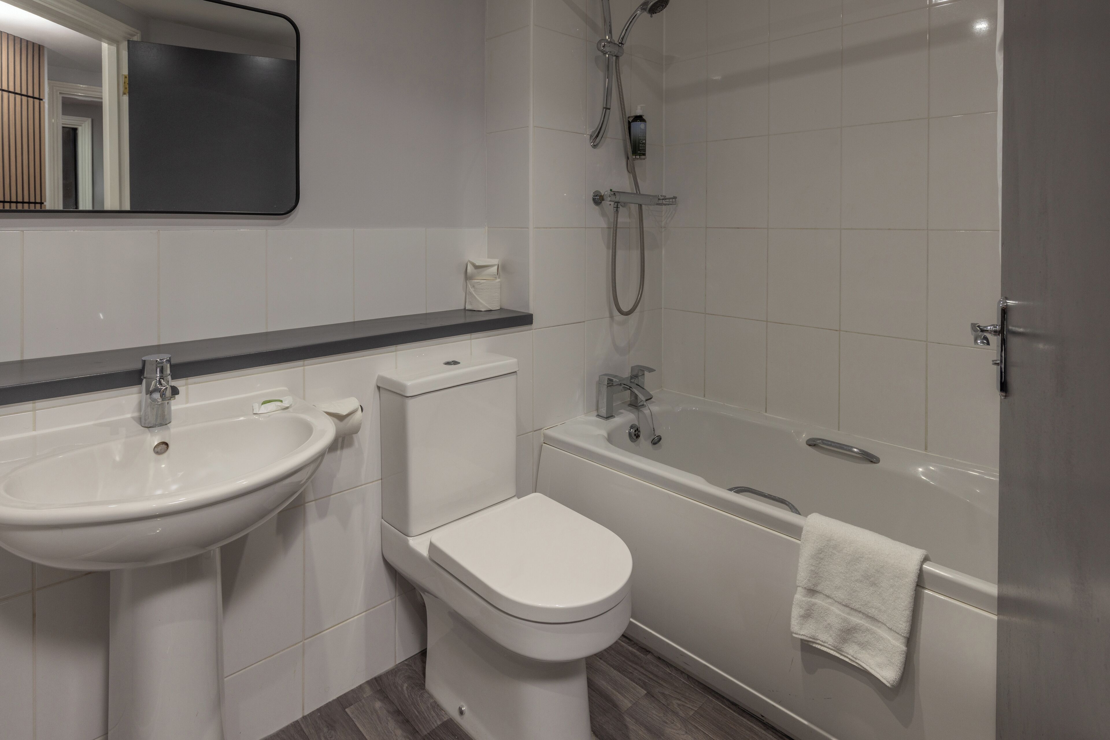 A modern bathroom with a sink, toilet, and bathtub.
