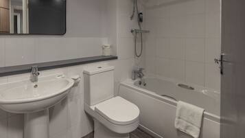 A modern bathroom with a sink, toilet, and bathtub.