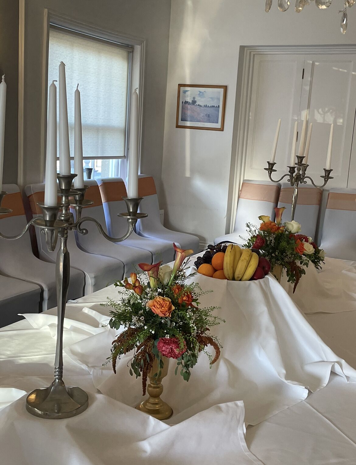Un comedor con manteles blancos, centros de mesa florales y candelabros.