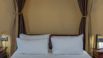 A bed with two white pillows, a wooden headboard, and a brown curtain with a polka dot pattern.