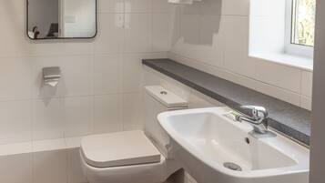 A modern bathroom with a white toilet, a sink, and a mirror.