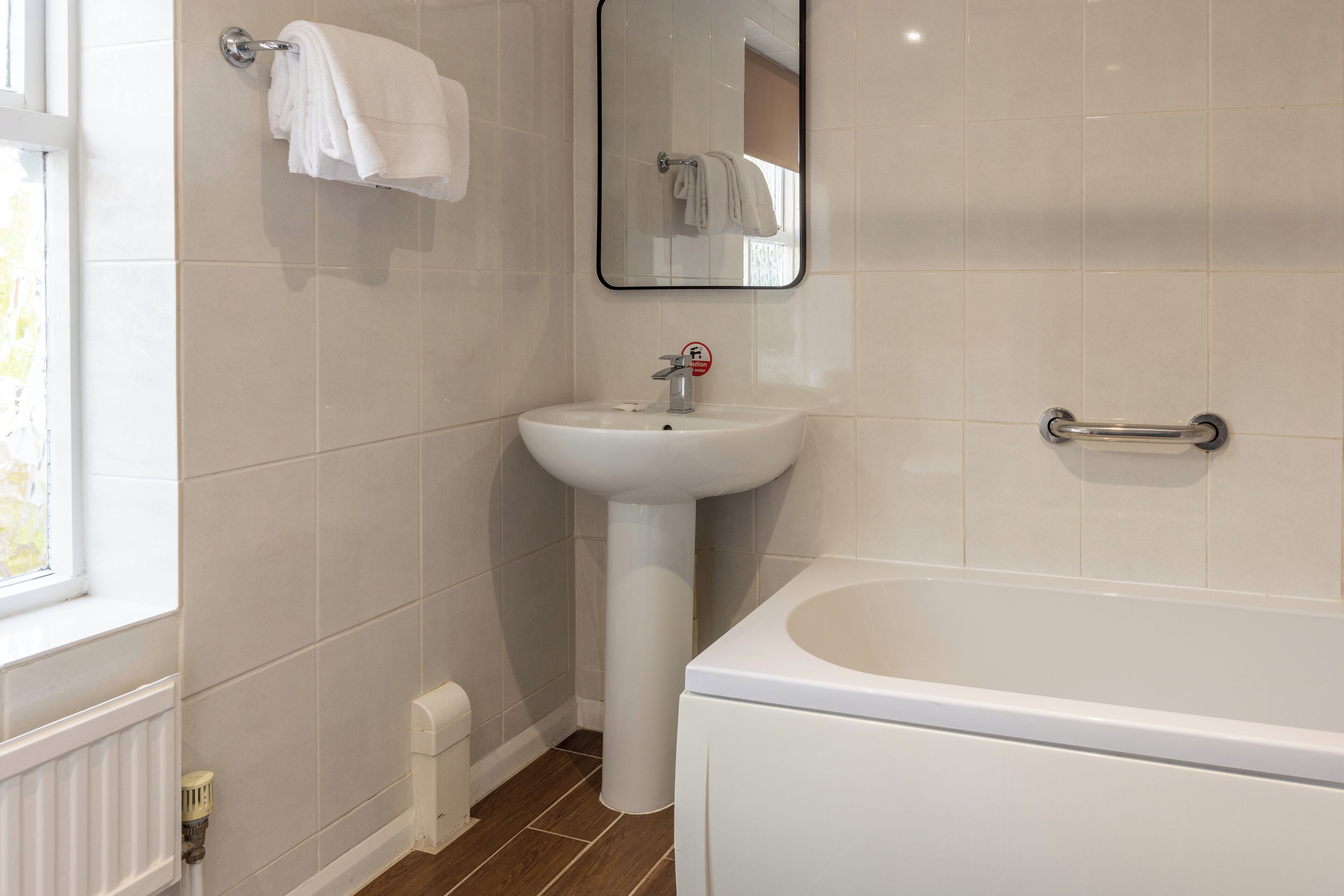 A bathroom with a white sink, a mirror, and a bathtub.