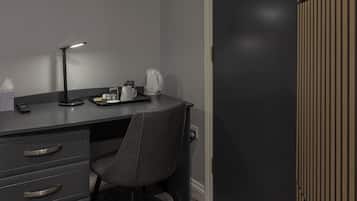 Un escritorio moderno con una silla, una lámpara de escritorio, una cafetera y un control remoto.