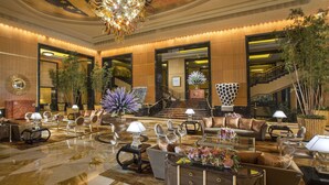 Un'ampia hall con un sontuoso lampadario, diverse zone relax e una scala che conduce a un piano superiore.