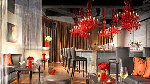Un'area bar moderna con sedute in pelle, un bancone e un lampadario.