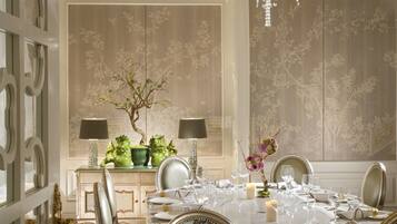 Un comedor formal con candelabro, sillas ornamentadas y una mesa dispuesta para seis comensales.