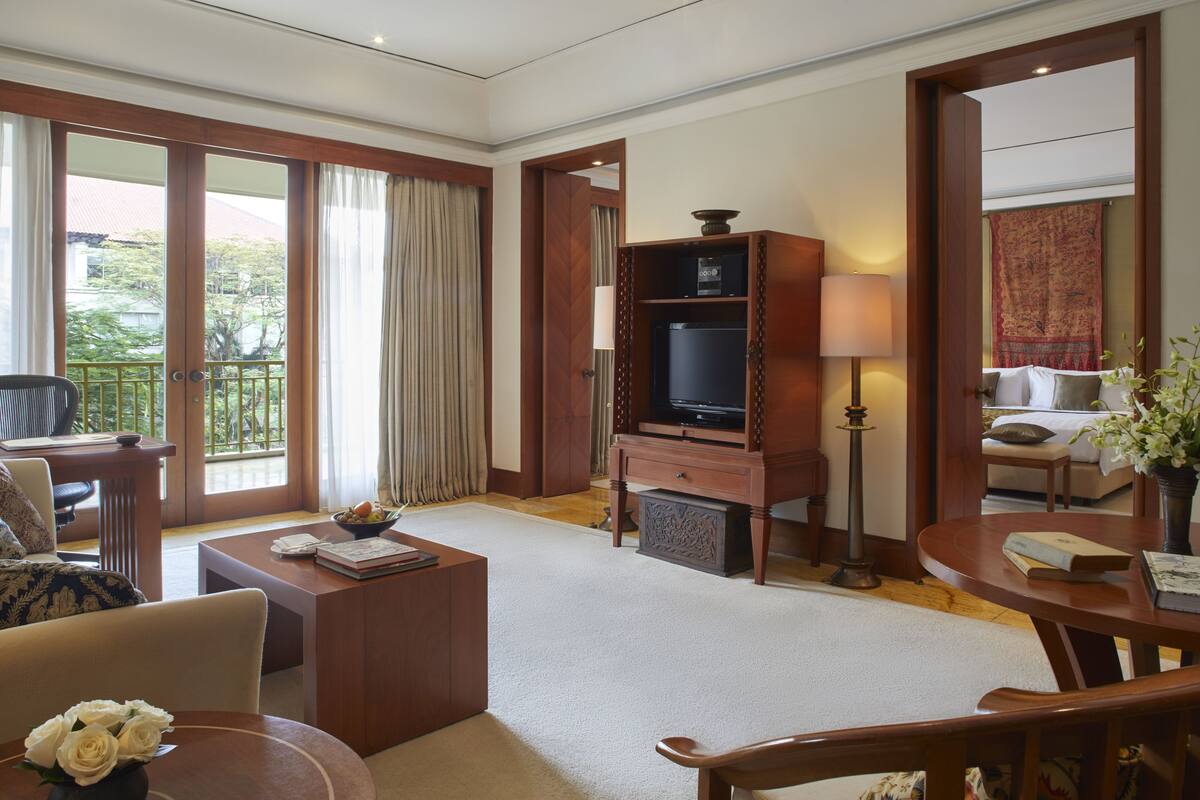 Ein Hotelzimmer mit einer Couch, einem Couchtisch, einem Fernseher, einer Lampe und einem Bett.