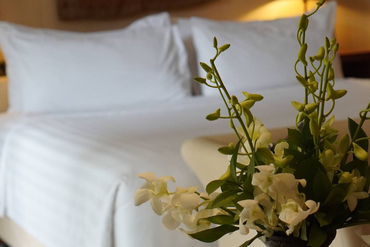 Ein Hotelzimmer mit Bett, Nachttisch mit Blumenvase und Lampe.