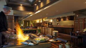 Un restaurante con decoración tradicional japonesa, que muestra a un chef preparando comida en una parrilla, muebles de madera y una zona de recepción.