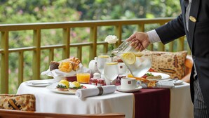 Un desayuno con una mesa dispuesta para dos, incluyendo platos con comida, una jarra de jugo de naranja y una tetera.