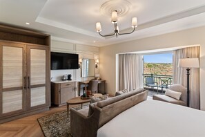 Een hotelkamer met een groot bed, een bureau, een kledingkast, een televisie en een balkon met uitzicht.
