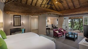A hotel room with a large bed, a desk, a chair, a television, and a balcony with a view of trees. - Mount Grace Hotel & Spa (Magaliesberg)