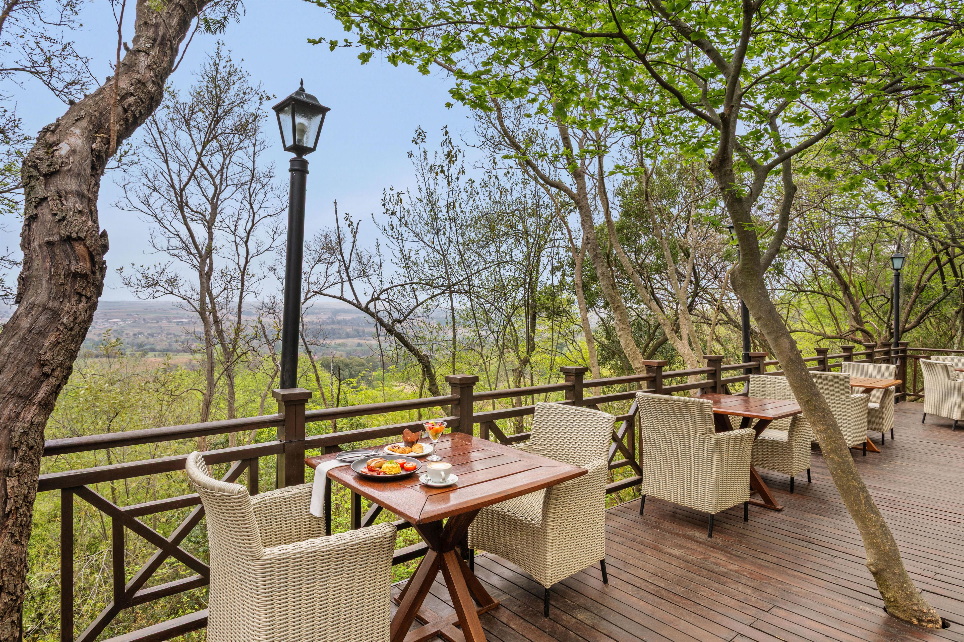 An outdoor dining area with wicker furniture and a view of the landscape.